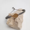 pulsera ameba gris verdoso, hecha a mano con hilo de poliéster encerado y pieza metálica con baño de oro. Cierre ajustable.