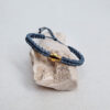 pulsera cruz esmeralda hecha a mano con poliéster encerado y pieza central con baño de oro, y cierre ajustable con nudo corredero