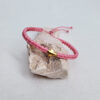 pulsera cruz rosa hecha a mano con poliéster encerado y pieza central con baño de oro y cierre ajustable con nudo corredero