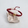 pulsera cruz vino hecha a mano con poliéster encerado y pieza central con baño de oro, cierre ajustable con nudo corredero
