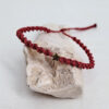 pulsera estrella vino, hecha a mano con poliéster encerado resistente al agua. Lleva una pieza en forma de estrella con baño de oro. Cierre corredero ajustable.