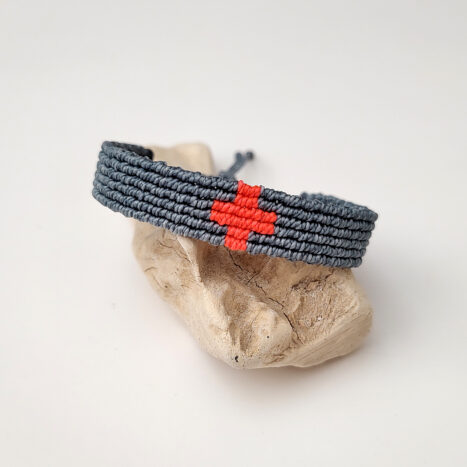 pulsera cruz nudos esmeralda y naranja flúor, hecha a mano con poliéster encerado resistente al agua y nudo corredero ajustable a la muñeca.
